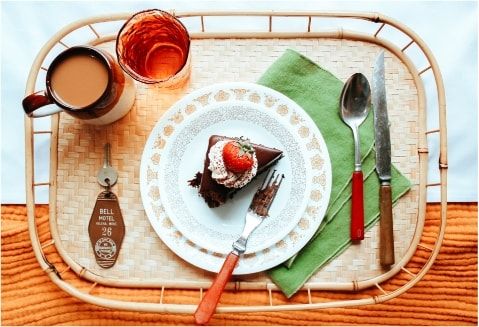 A room service tray with a slice of chocolate cake and a room key.